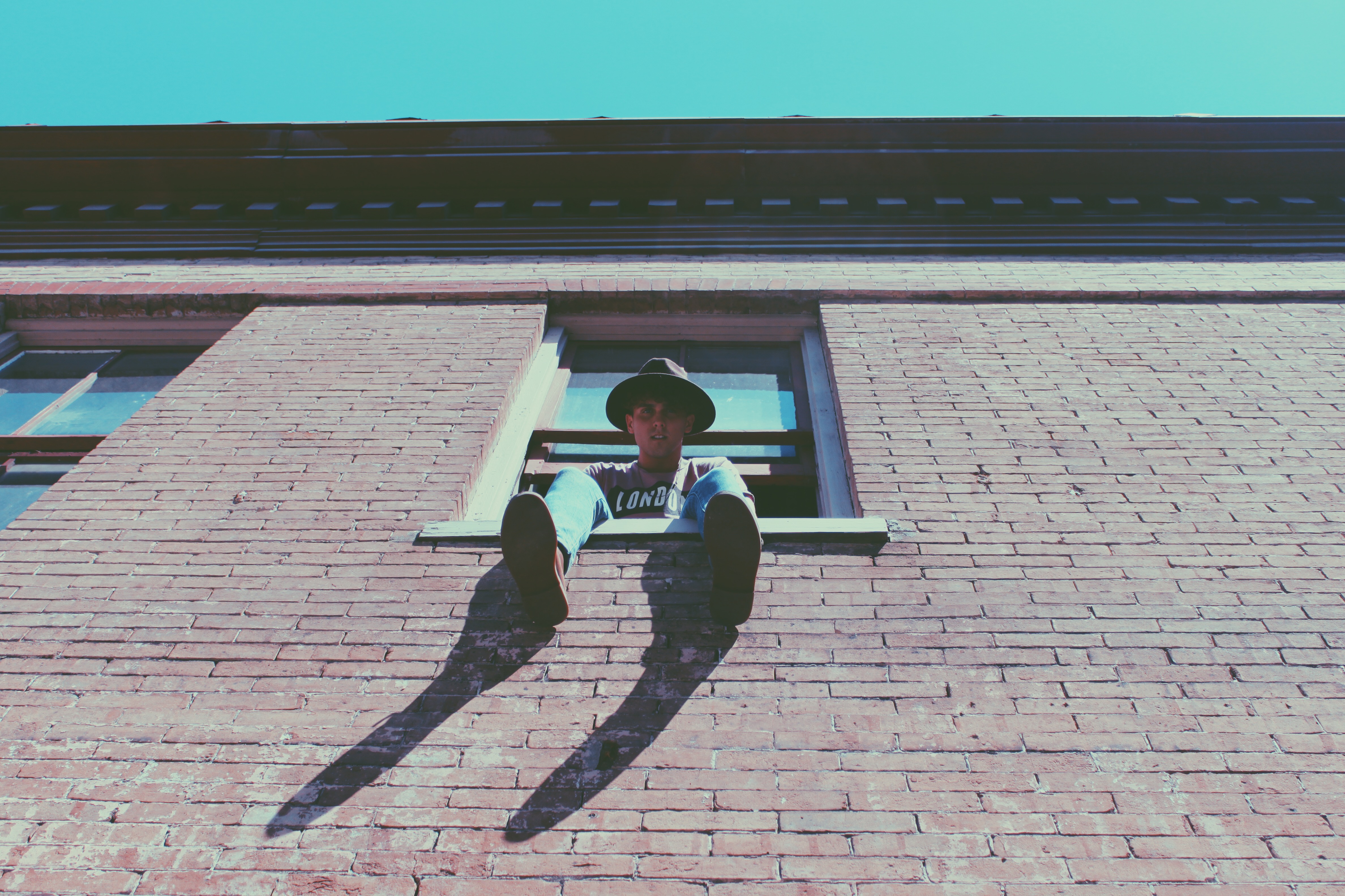 low angle photography of man sitting on window during daytime